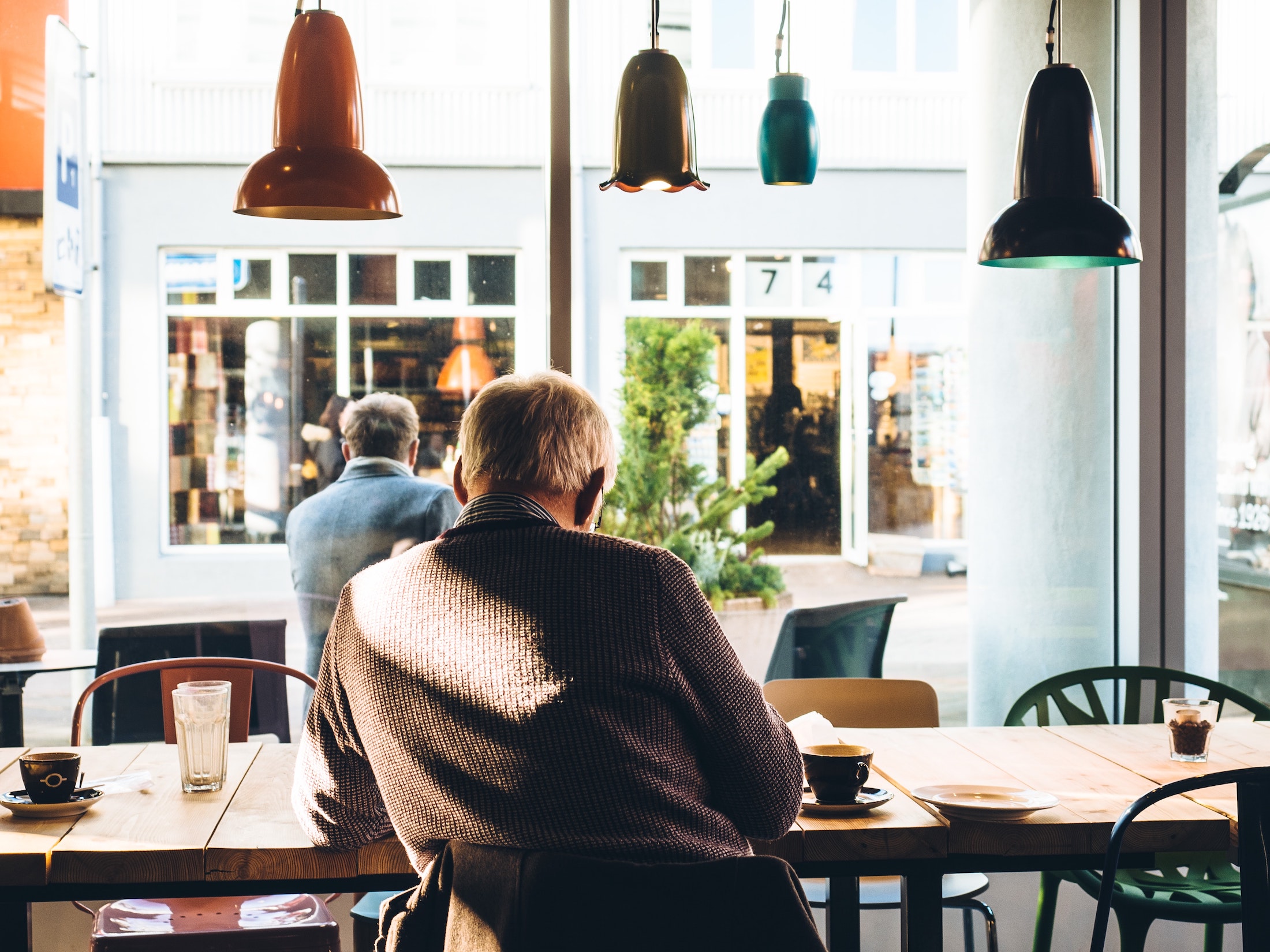 Person sitting at a desk in a coffee shop drinking a coffee